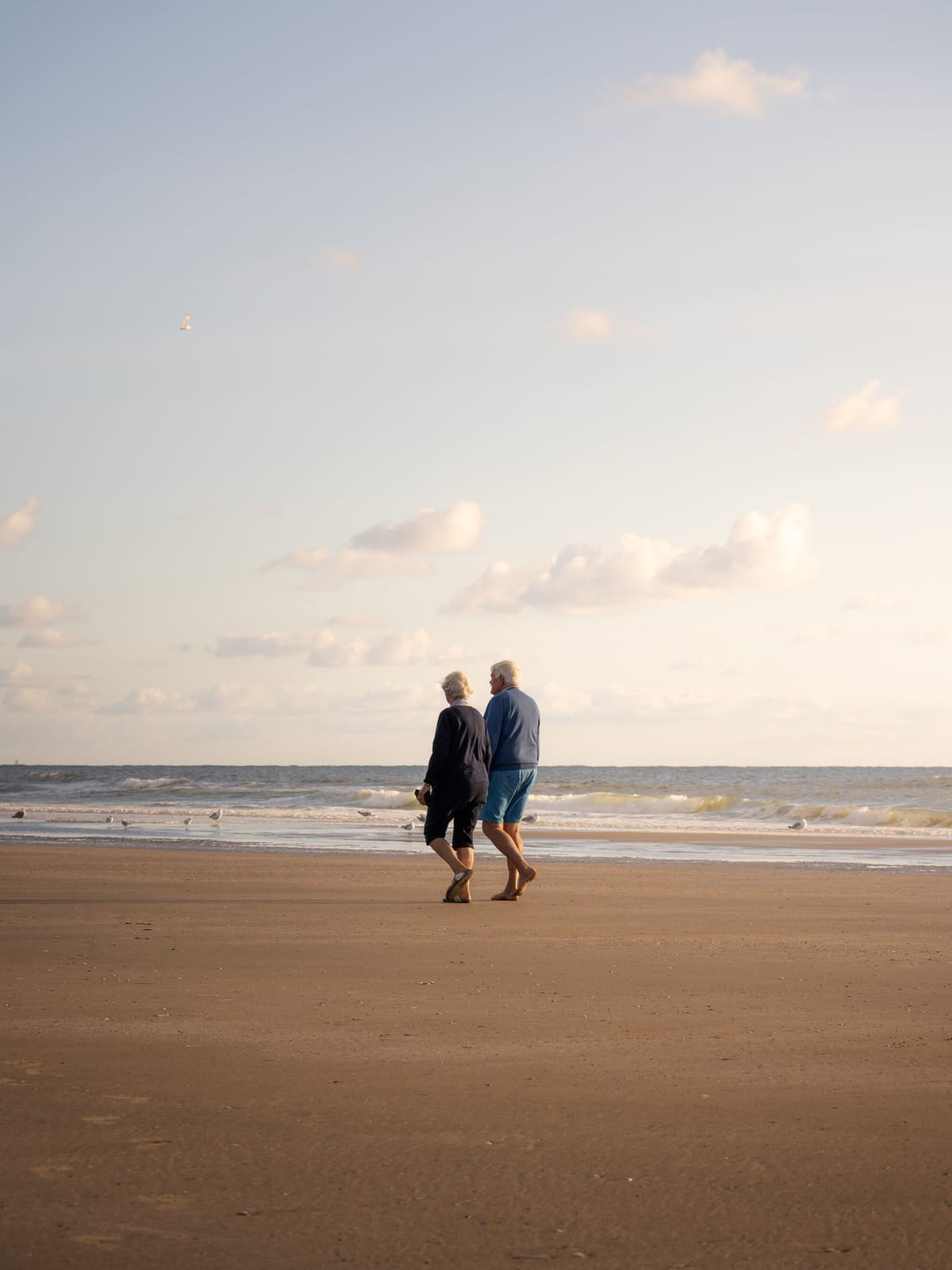 Et par går langs stranden en vinterkveld