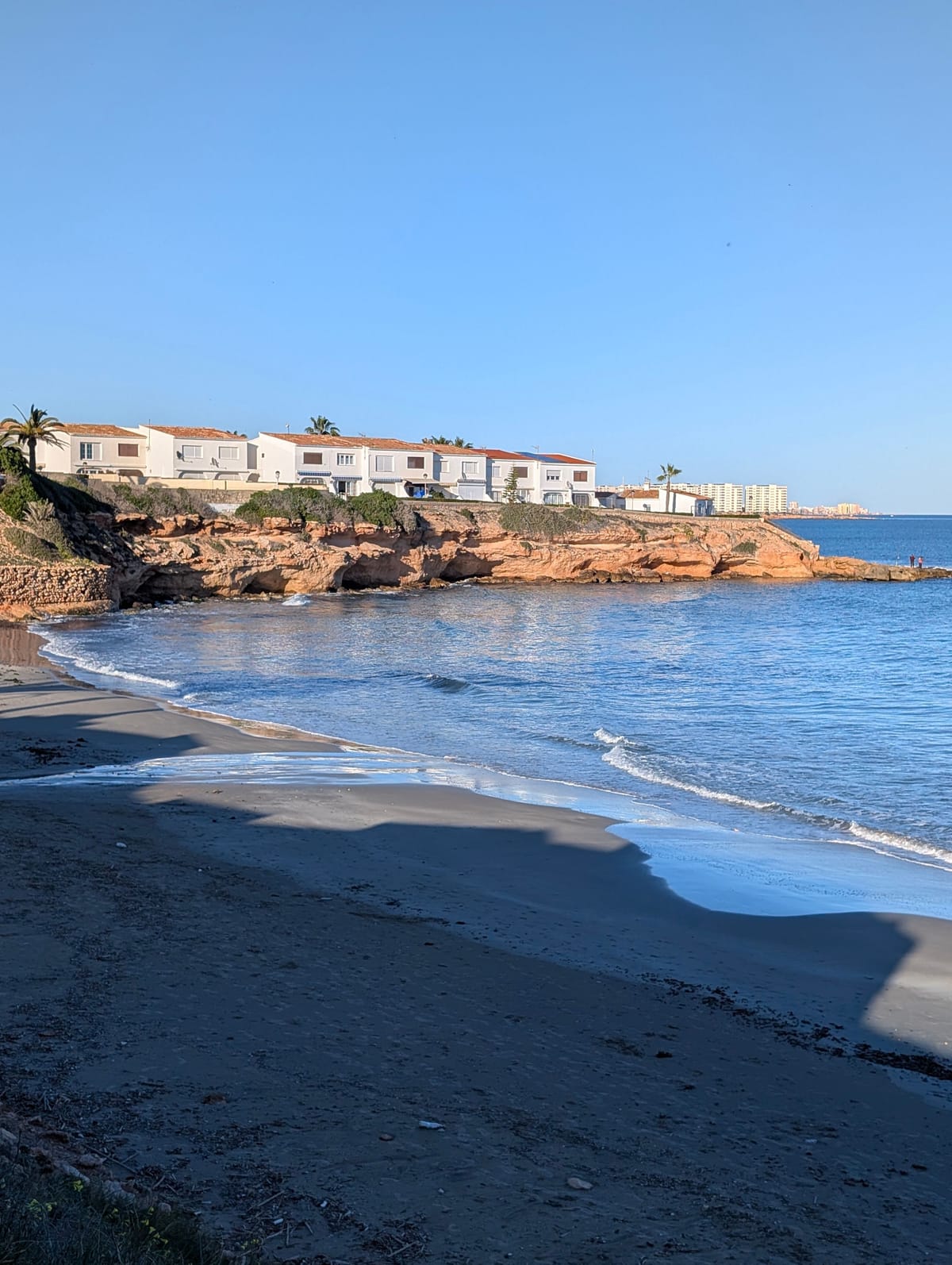 Liten bukt med røde klipper og hvite rekkehus på Costa Blanca